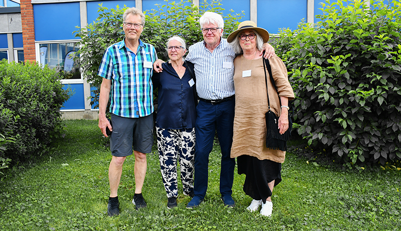 Två män och två kvinnor framför skolbyggnad.