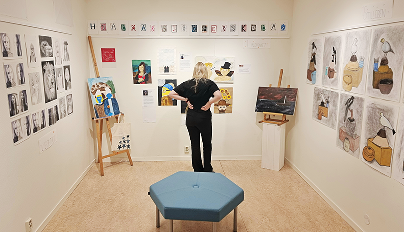 Kvinna tittar på konstverk på galleri.
